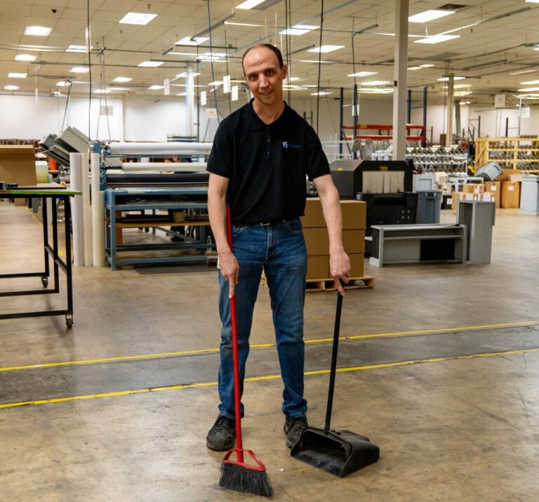 Employee sweeping warehouse floor.