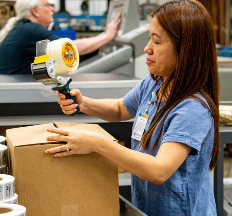 Print Source employee packing a custom roll label order.